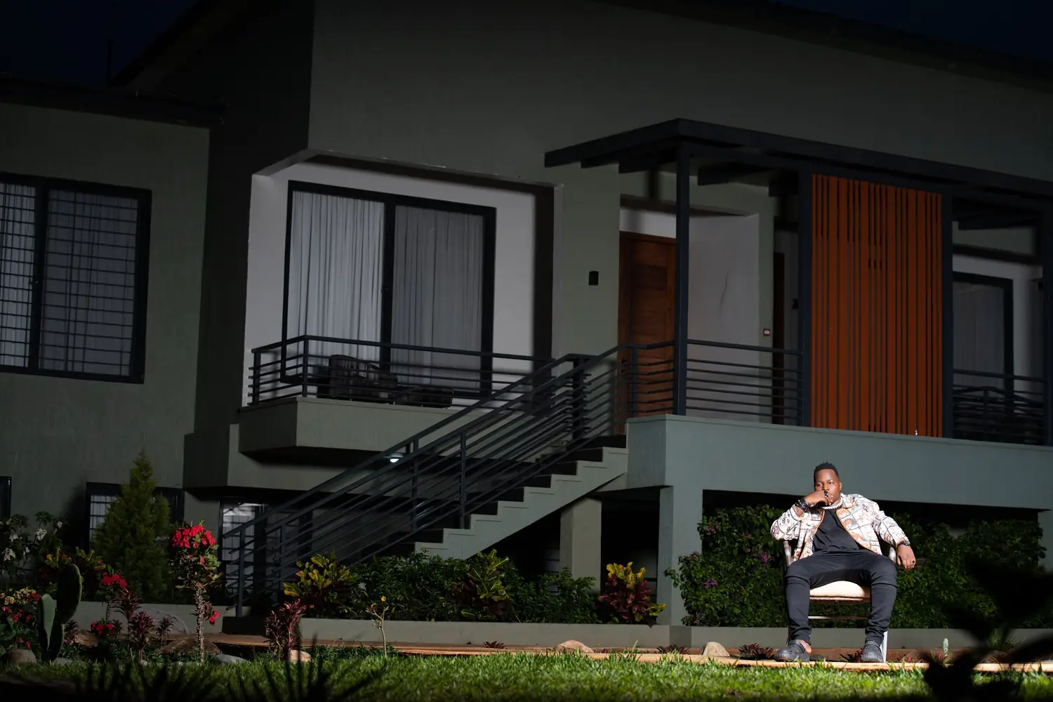 A man seated outside a modern house for a personal brand shoot